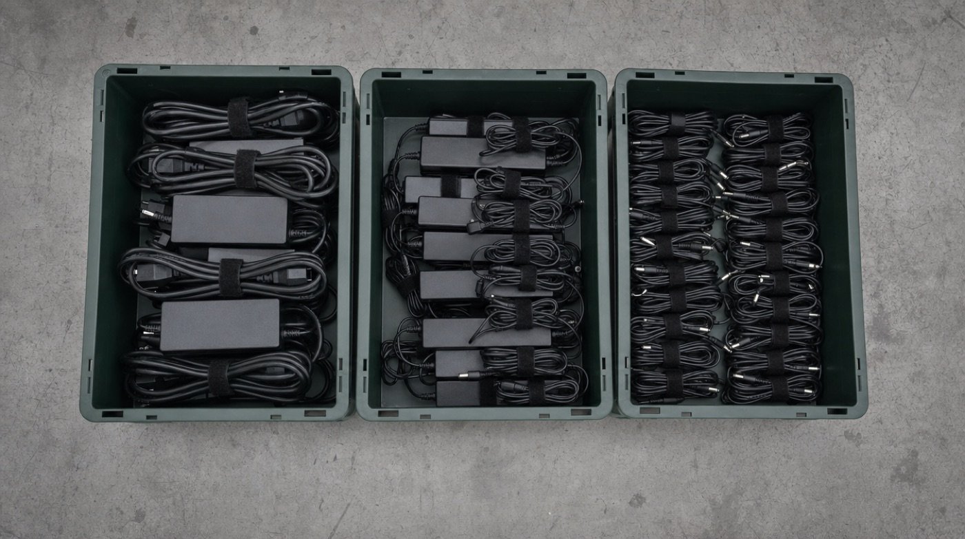 Three bins seen from above holding neatly coiled power adapters and cables, sorted by size.