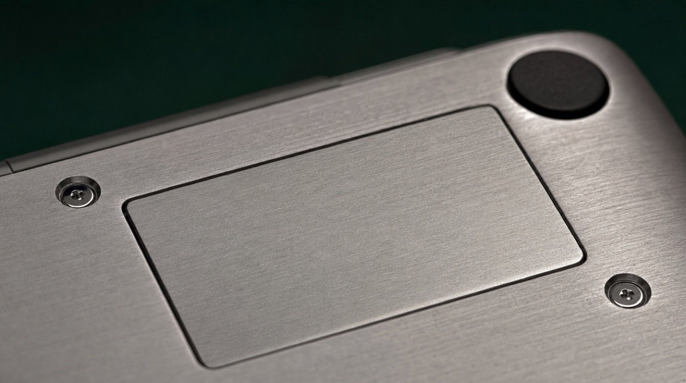 Extreme close-up of the brushed aluminium underside of a laptop showing a blank metal plate and two screws.